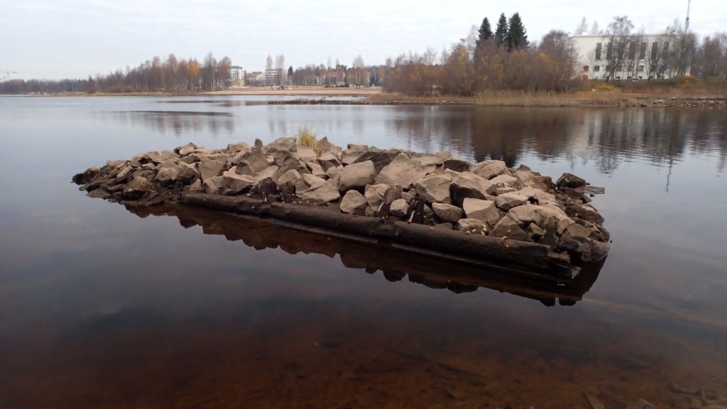 Jos vesi on normaalikorkeudella, näkyy tässä vain kivinen saari. Veden alta esiin tulleet puurakenteet paljastavat, että tässä on vanha kiviarkku, joka lienee peräisin ajalta, jolloin Oulujoessa uitettiin puuta.